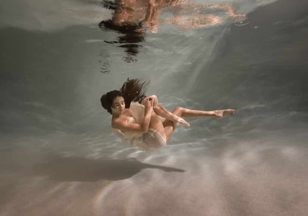 woman sinking underwater wearing a mini dress