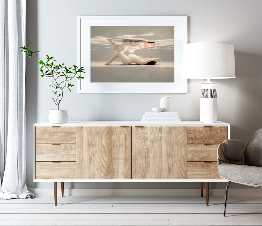 framed photo of a nude pregnant woman, displayed above a sideboard