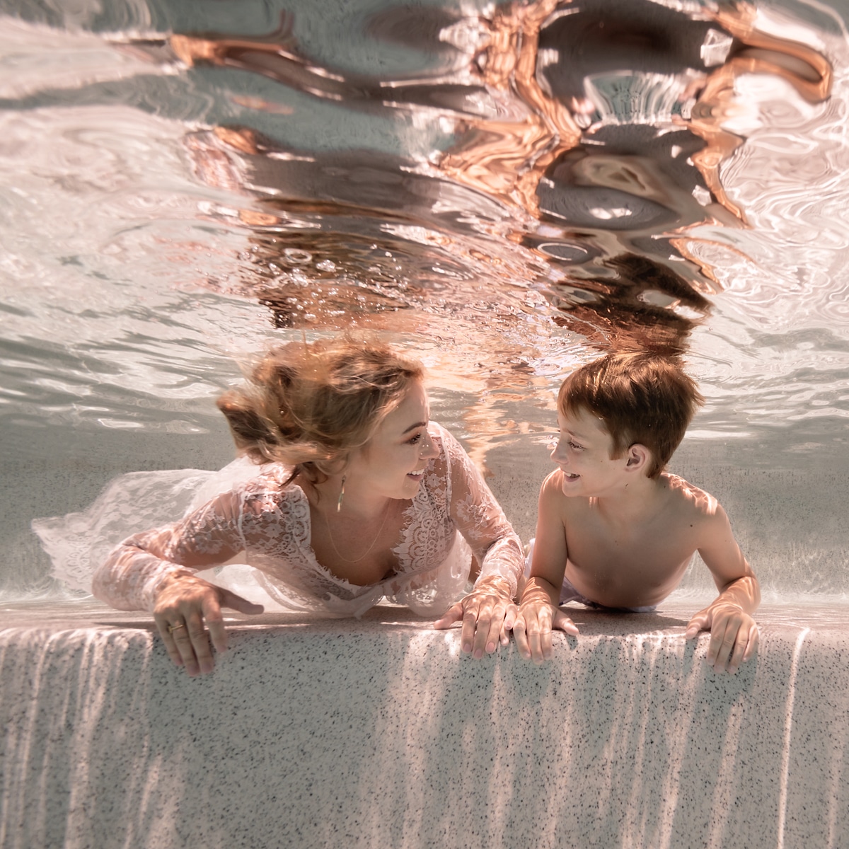 mother and son in a swimming pool underwater looking at each other